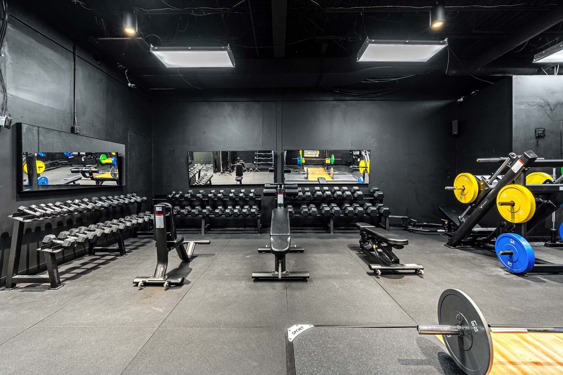 Wide dumbbell hall with adjustable benches and mirrors