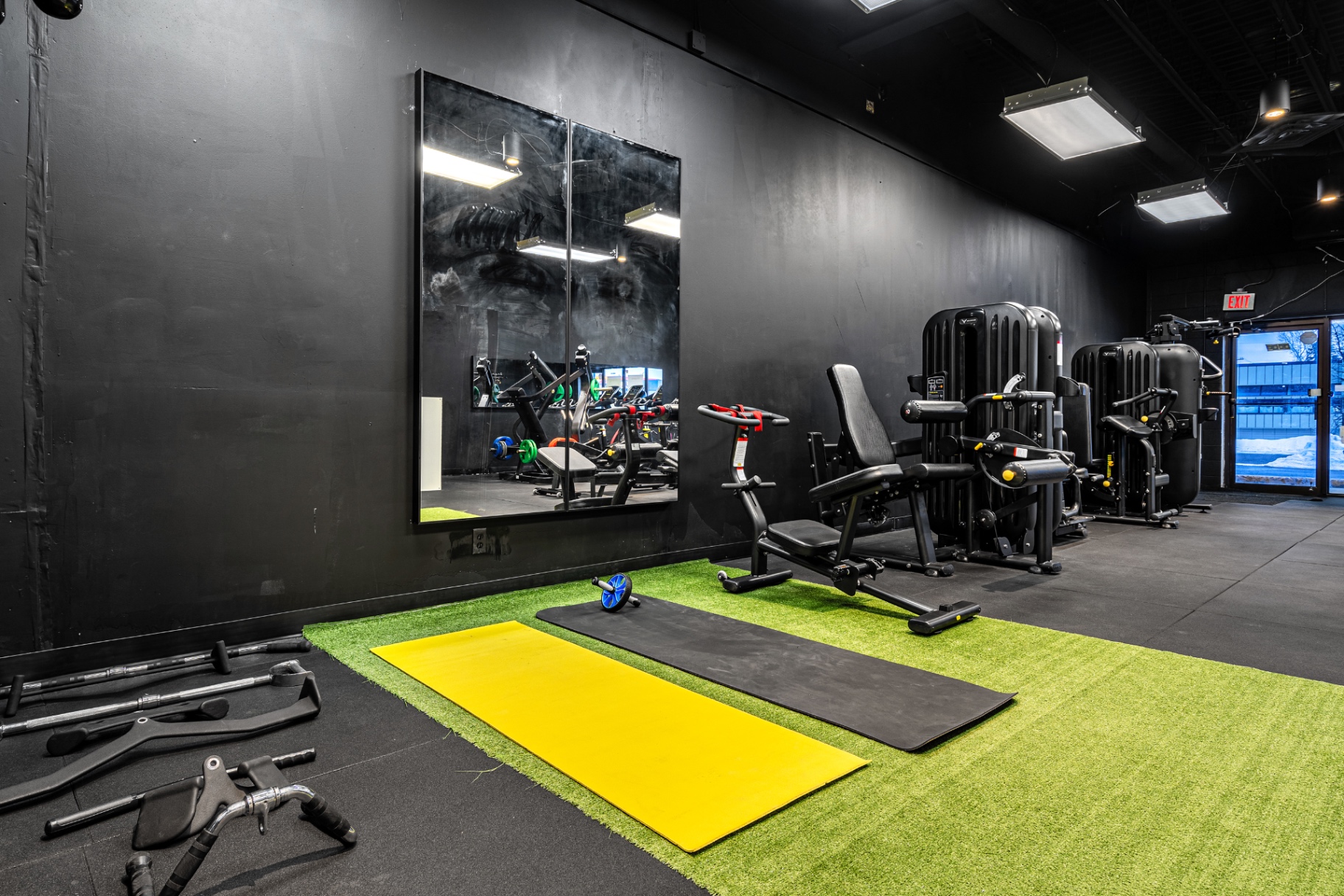 Selectorized leg machines beside the turf stretching area at Elk Fitness